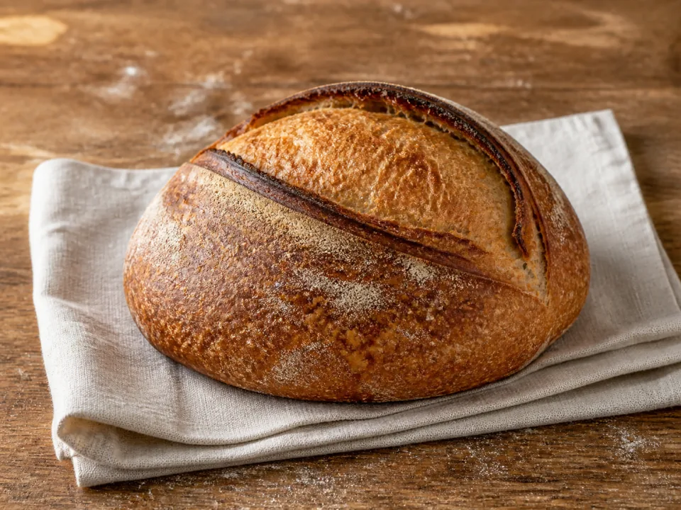 A handcrafted sourdough loaf on soft baker’s linen